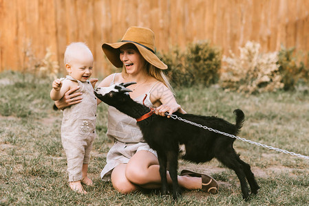 身戴帽子的幸福母亲和小儿子在农村青草上图片