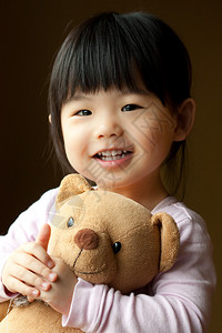 微笑的小孩手里拿着一只泰迪熊图片