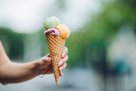 女人手拿着三种颜色的美味五颜六色的冰淇淋图片