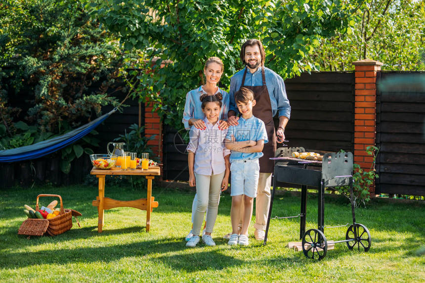 快乐的家庭看着摄影机夏日在后院烧烤图片