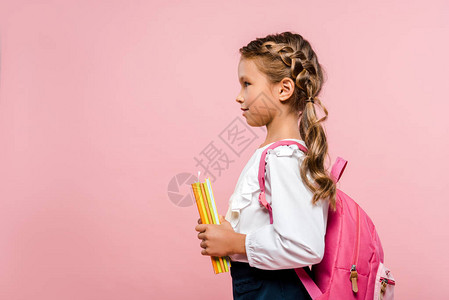 快乐的孩子拿着书站在粉色隔离的背图片