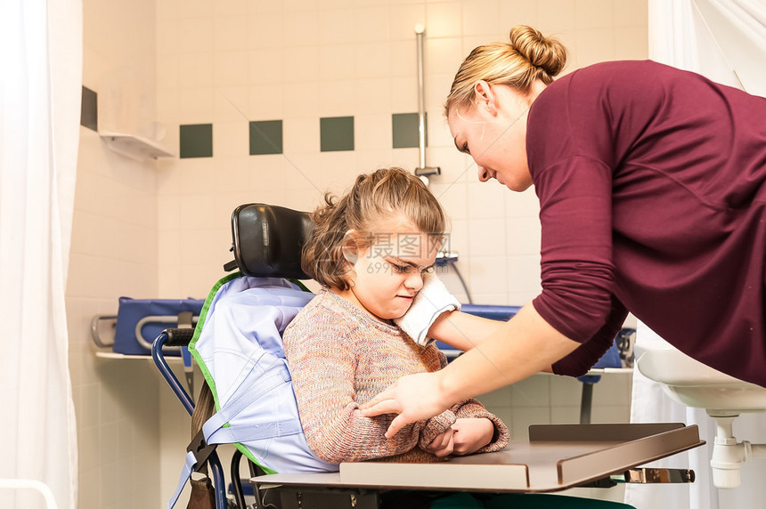 一名轮椅残疾女孩由护士照顾在轮椅上工图片