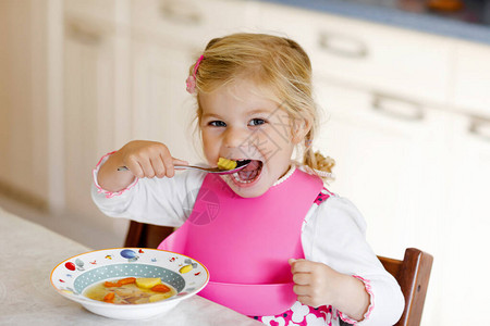 可爱的蹒跚学步的女孩午餐吃健康的蔬菜餐图片