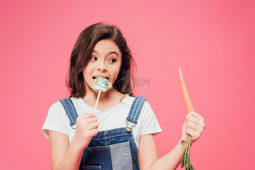 快乐的孩子吃棒糖看着被粉红色图片