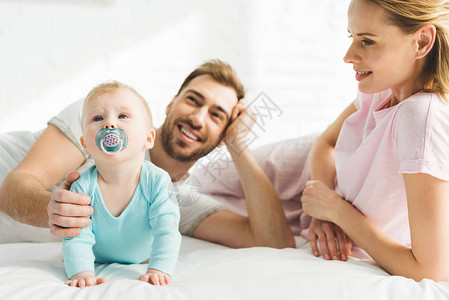 父母和婴儿女在床上带着图片