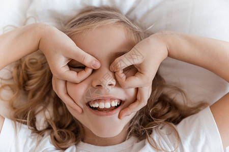 笑可爱的小孩躺在床上展示眼镜手势图片