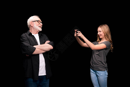 微笑的祖父和孙女拍摄用智能手机在图片