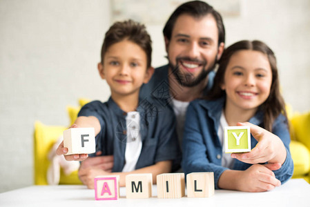 和两个可爱的小孩一起快乐的父亲带着有字词的家庭立方体图片