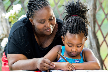 近距离拍摄非洲母亲在户外做家庭作业的肖图片