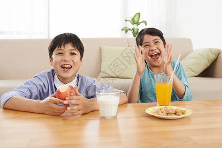孩子们在吃早餐时兴奋地看电视图片