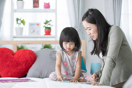 幸福的亚洲家庭怀孕母亲和女婴在家里读图片