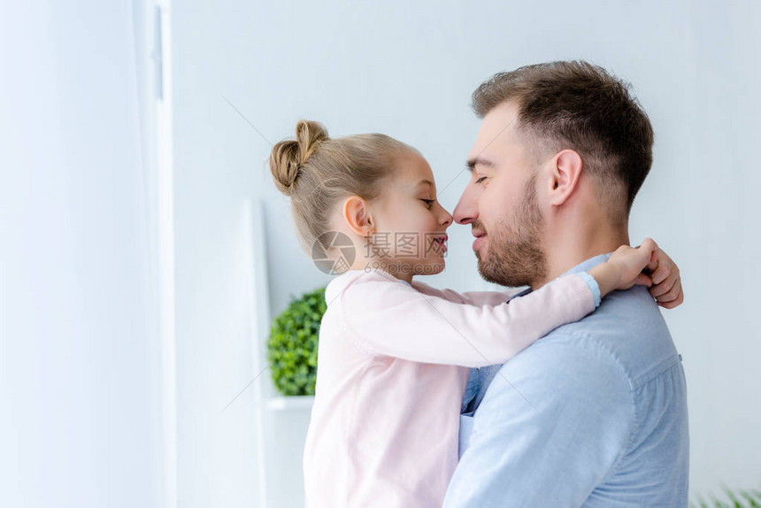 拥抱和触摸鼻子的父子女孩图片