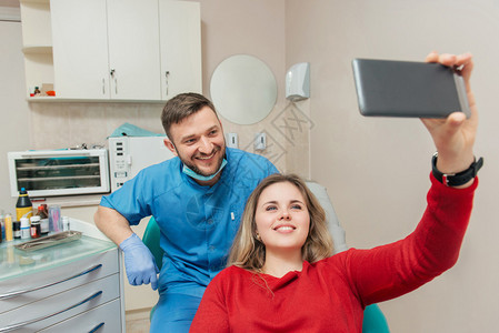 有雪白微笑的病人和牙医在牙科办公室做自图片