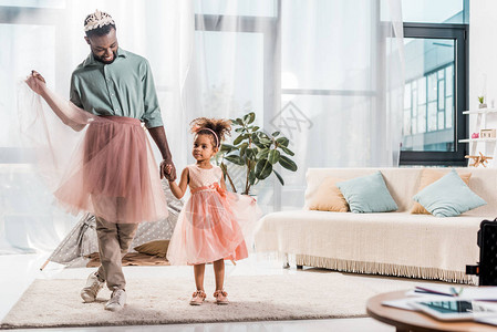 穿着可爱粉色短裙的快乐非洲裔美国父亲和穿着漂亮裙图片