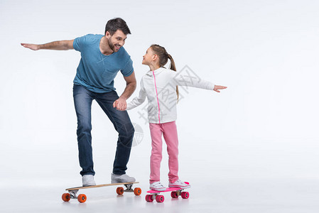 父亲和女儿微笑骑着滑板在图片