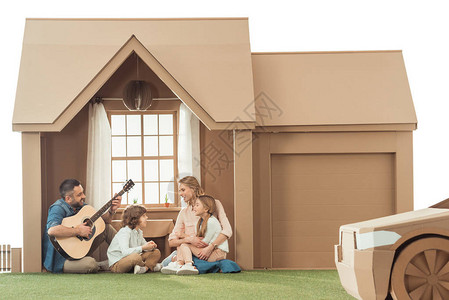父亲弹吉他给孩子和妻子在新的纸板图片