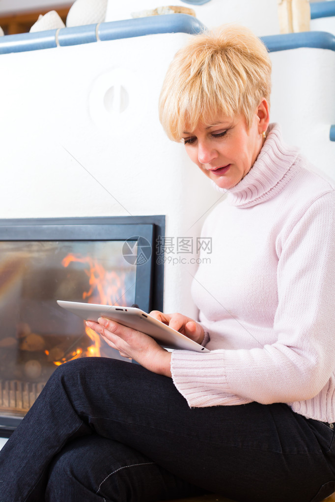 坐在家里炉前的老年妇女或养老金领取者图片