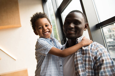 快乐的非洲美国父亲和可爱的小儿子拥抱和图片