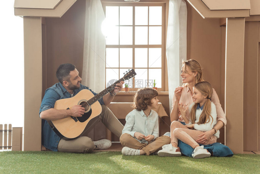在新纸板屋里为家人弹吉他的男人图片