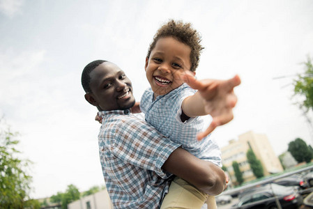 欢乐的非洲父亲和儿子拥抱着在街上对着摄影图片