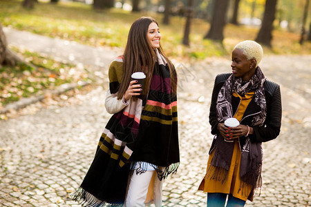 两个年轻漂亮的多种族女友在秋日喝咖背景图片