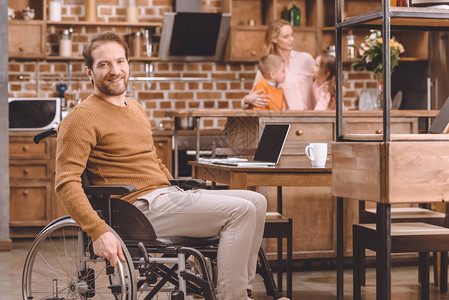 坐在轮椅上的残疾中年男子在家里与家人共度时光图片