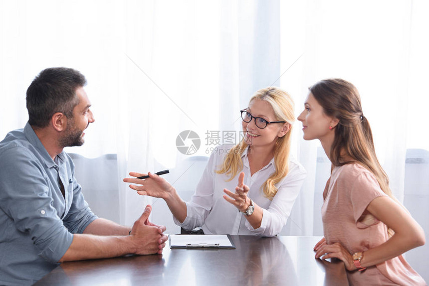 女律师在办公室的心理治疗课上用手亲引导和与夫妇交谈时微笑着图片