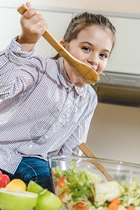 带勺子的小孩在厨房的碗里吃沙拉图片