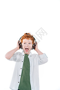 小红发兴奋的男孩戴着耳机听音乐图片