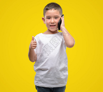 黑发小孩用智能手机开心地笑着做好手势图片