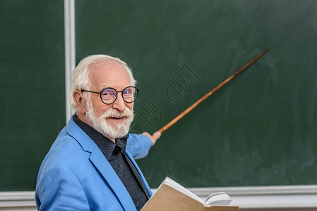 灰色头发教授拿着书指着图片