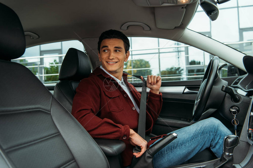 手持安全带的微笑者在汽车中举起安全带图片