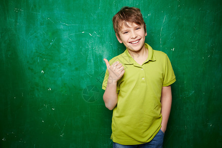站在黑板旁时微笑的男孩大拇指露图片