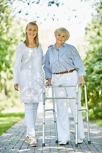 微笑的护士和年长的病人用步行架子看着图片