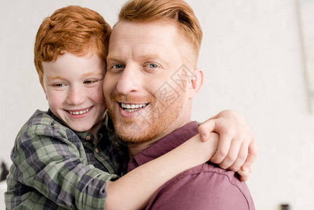 快乐的红发父亲和儿子抱在家图片