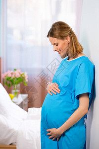 快乐的天主教孕妇抚摸她的肚子站图片