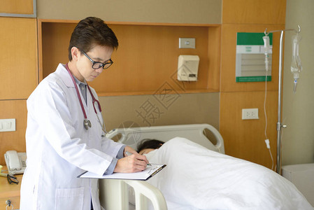 女医生在医疗病历上写作病人躺图片