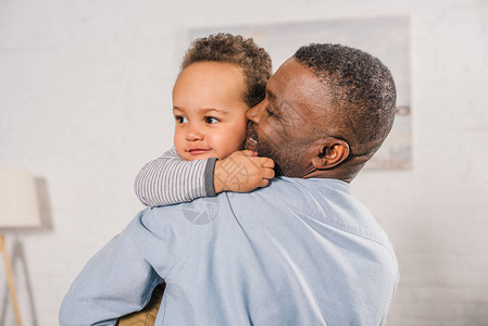 在家拥抱可爱的小孙子的愉快的非裔背景图片