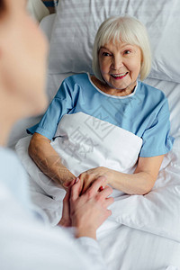 与在医院床上躺在床上的快乐老年妇女图片