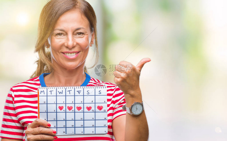 中年西班牙裔老年妇女在孤立的背景下拿着月经日历图片