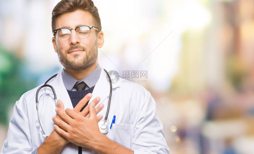 年轻英俊的医生在与世隔绝的背景下微笑着双手放在胸前图片