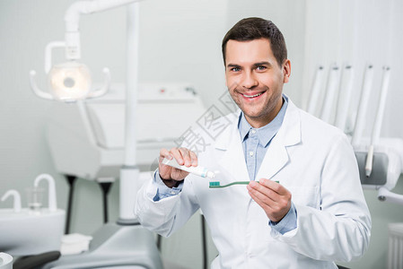 牙医在牙科诊所牙刷上挤牙膏图片