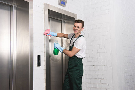 英俊的年轻清洁青年洗涤电梯图片