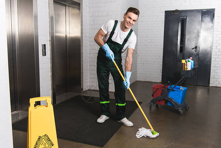 年轻英俊的清洁工擦地板背景图片