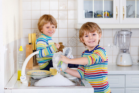 有趣的双胞胎男孩在厨房帮忙洗碗孩子们在做家务时很开心室内图片