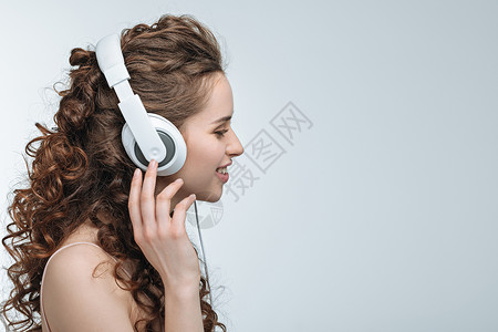 有吸引力的年轻女子在白色孤立的耳机中监图片
