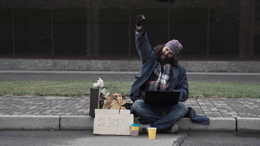 有趣的无家可归乞丐使用笔记本电脑图片