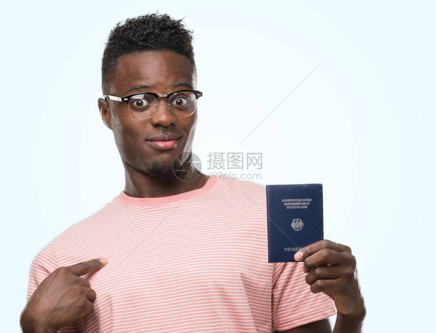 持有德国护照的年轻非洲美国人用奇异的脸向自己指图片