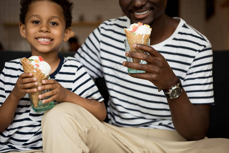 在咖啡馆吃冰淇淋的非洲父亲和儿子笑着拍图片