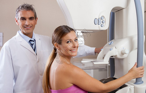 30多岁的年轻妇女在乳房造影机上与快乐的男医生进行扫图片